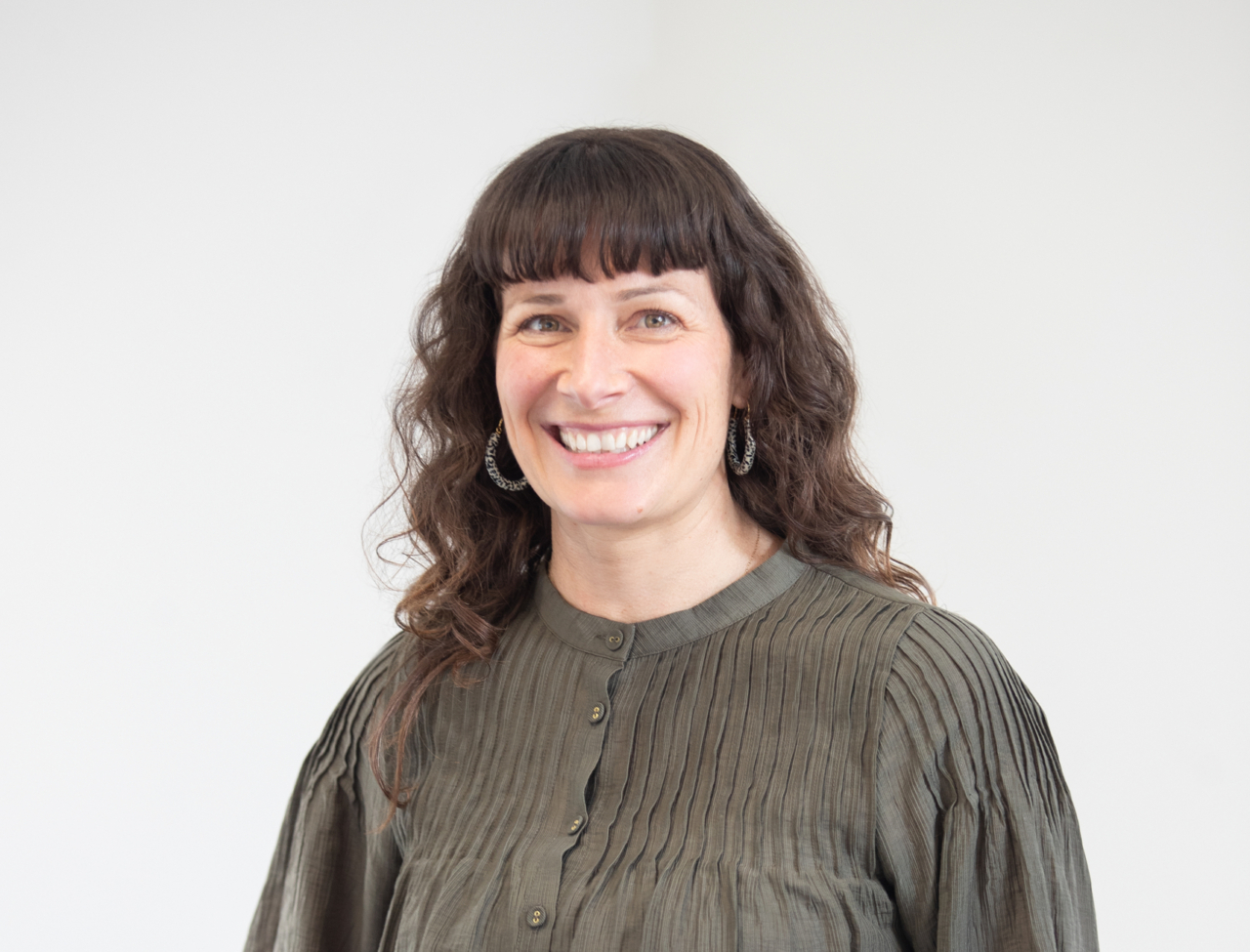 Photo of senior analyst Mel Wilson standing in an olive-green blouse against a plain background