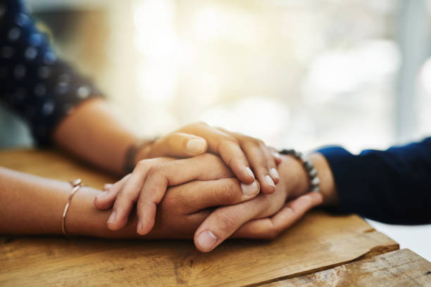 One person clasping another's hands in a supportive gesture