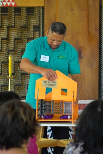 Man in Te Whare t-shirt putting front on marae