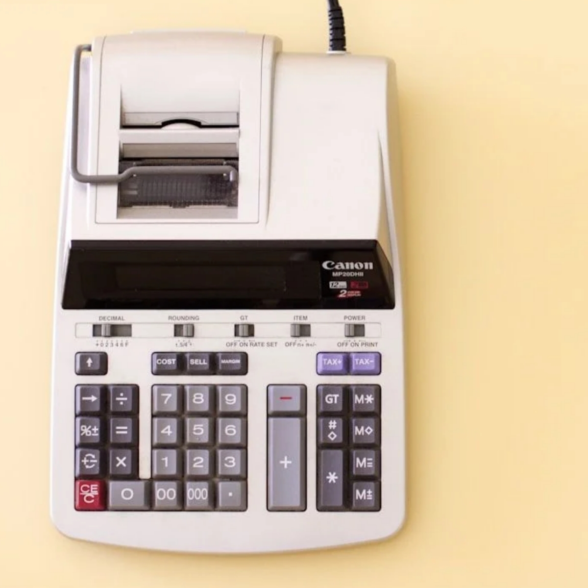 White accounting calculator on light yellow background