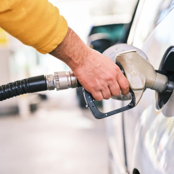 Closeup of person's hand pumping petrol into white car