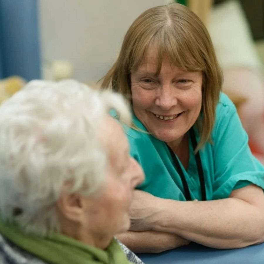 Female carer in green smiling with older person