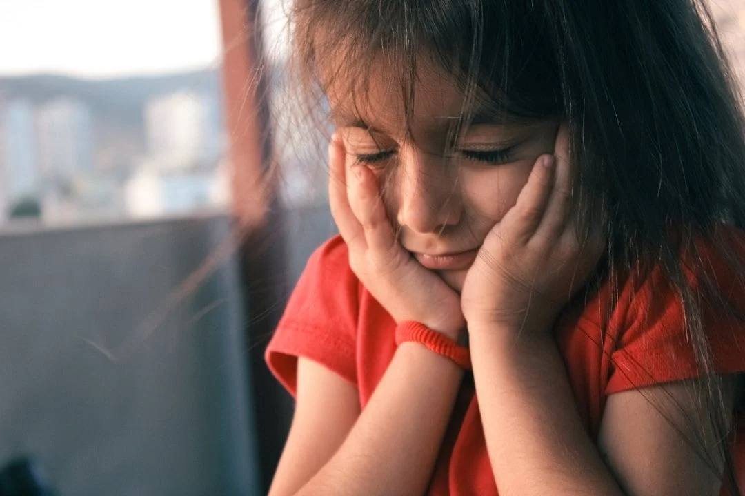 Girl in red t-shirt with head in hands
