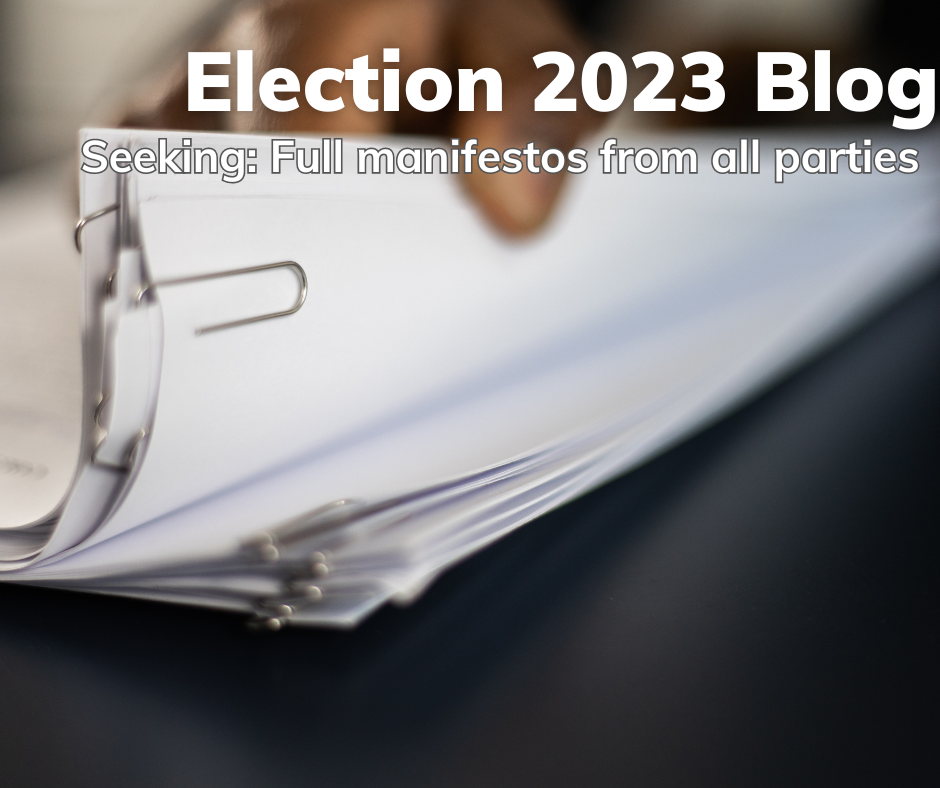This postcard has the words: Election 2023 Blog - Seeking: Full manifestos from all parties over the top of a picture of a hand leafing through some paper documents.