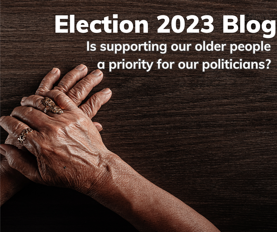 This postcard has the words: Election 2023 Blog - is supporting our older people a priority for our politicians? Below the words is an image of the hands of older people clasp each other on a table.